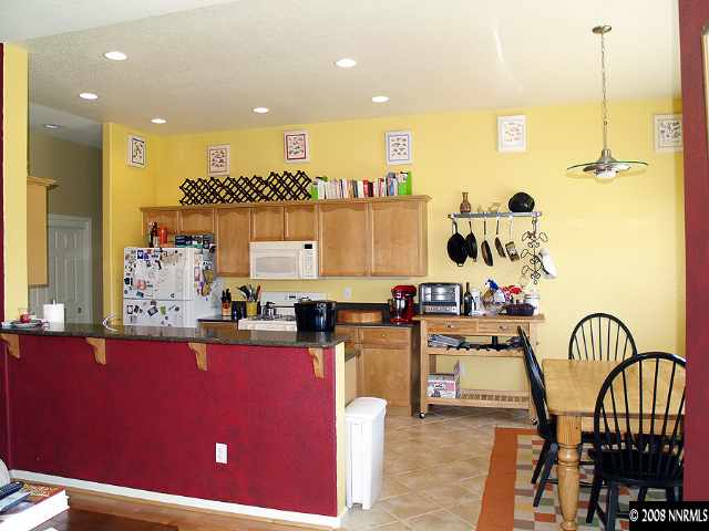 1725 Big Boulder Court Reno, NV 89521 - Photo 3 of 9 a kitchen with stainless steel appliances kitchen island granite countertop a stove a sink and a dining table with wooden floor