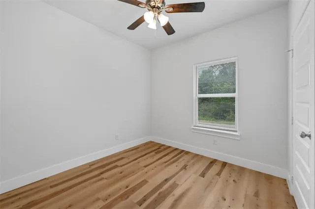 an empty room with a window and a ceiling fan