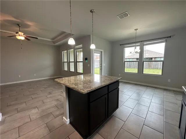 a kitchen with kitchen island a chandelier wooden cabinets and appliances