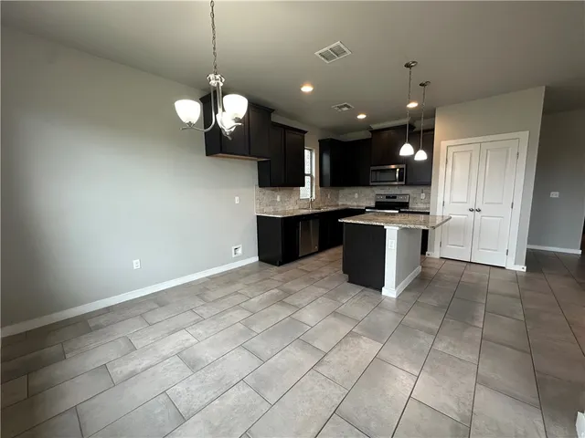 a large kitchen with granite countertop a stove top oven a sink a counter and cabinets