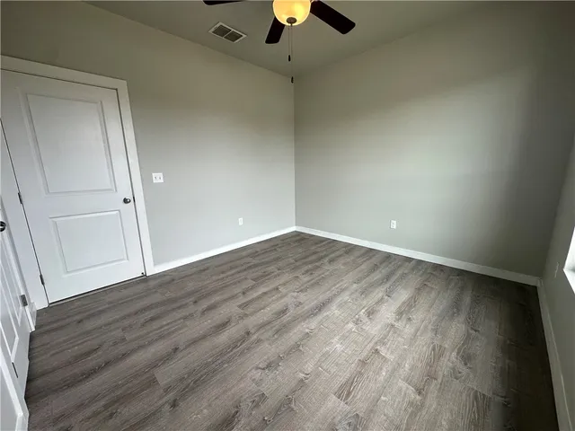 wooden floor in an empty room with a chandelier fan
