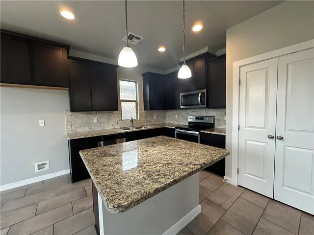 a kitchen with stainless steel appliances granite countertop a sink a stove a refrigerator and a oven