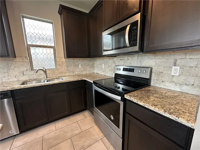 a kitchen with stainless steel appliances granite countertop a stove microwave and sink