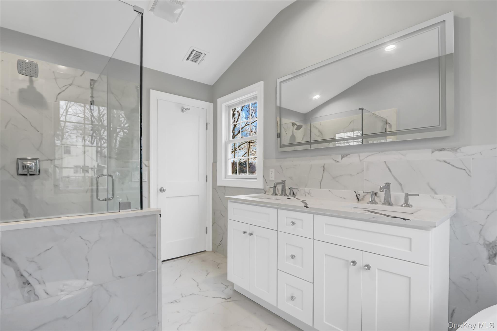 9 Hickory Road Bayville, NY 11709 - Photo 22 of 40 a bathroom with a double vanity sink a mirror and a bathtub