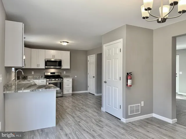 a kitchen with stainless steel appliances granite countertop a refrigerator a stove top oven a sink and dishwasher with wooden floor