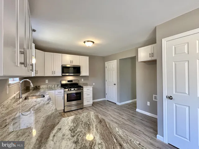 a kitchen with granite countertop a refrigerator and a stove top oven