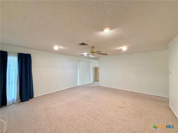 an empty room with an entryway and fan