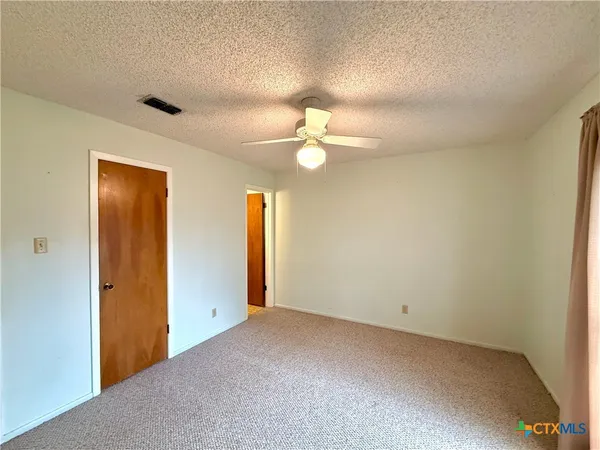 a view of an empty room with a chandelier fan
