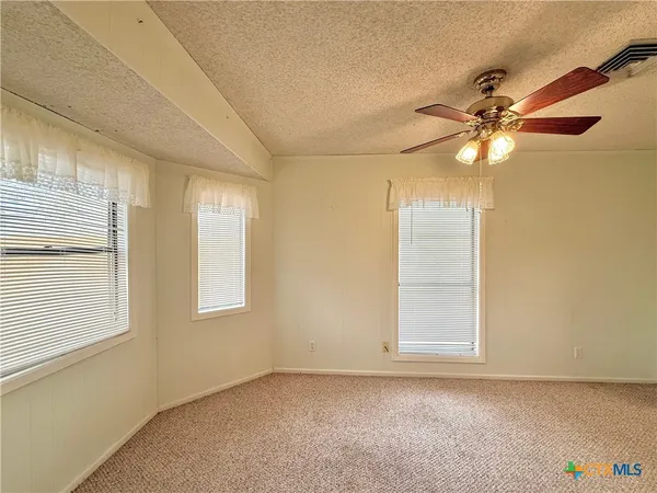 an empty room with windows and fan
