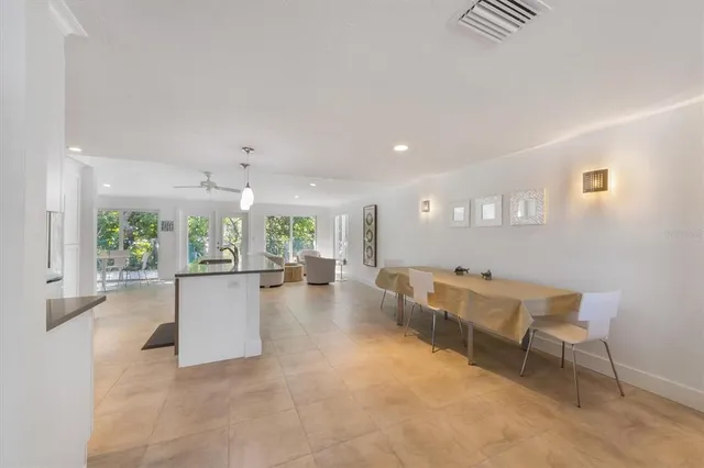 a kitchen with stainless steel appliances granite countertop a stove top oven a sink dishwasher a dining table and chairs with wooden floor