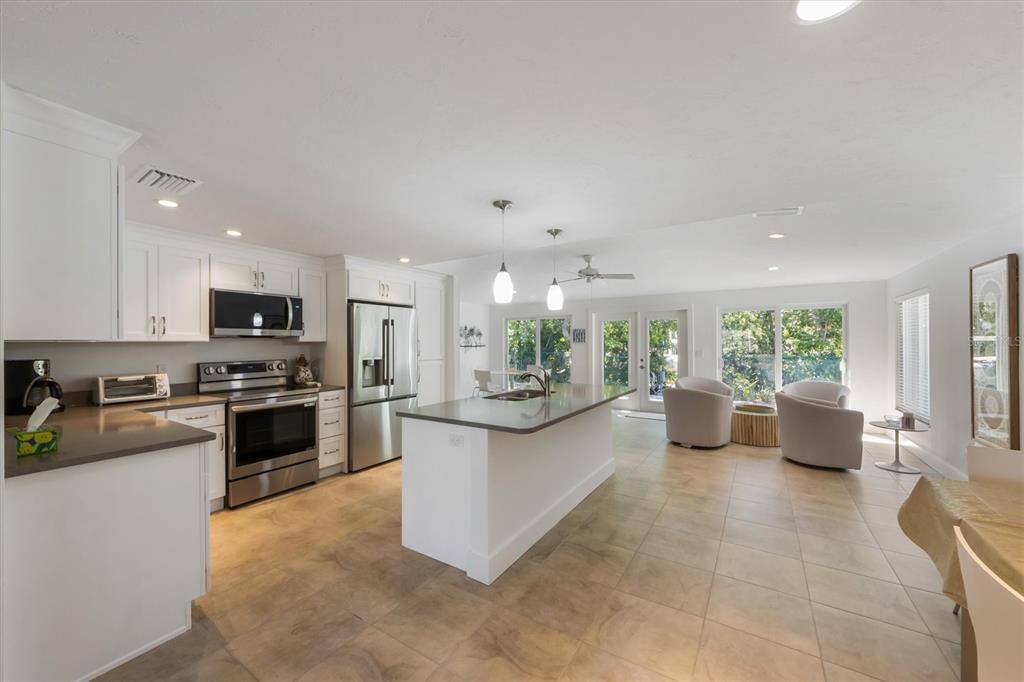 413 Poinsettia Road Anna Maria, FL 34216 - Photo 8 of 60 a kitchen with stainless steel appliances granite countertop a stove top oven a sink dishwasher a dining table and chairs with wooden floor