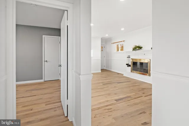 a view of a hallway with wooden floor and a refrigerator