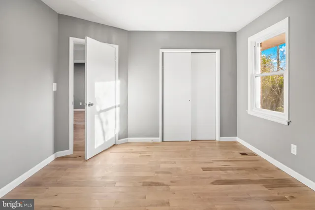 a view of an empty room with window and wooden floor