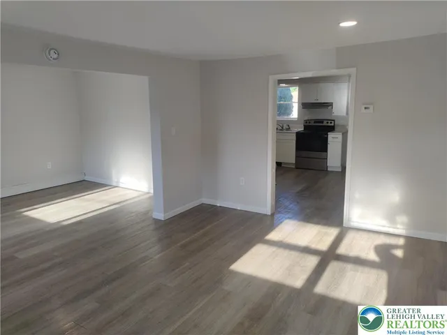 a view of empty room with kitchen and window