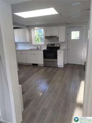 a kitchen with a white cabinets and wooden floor
