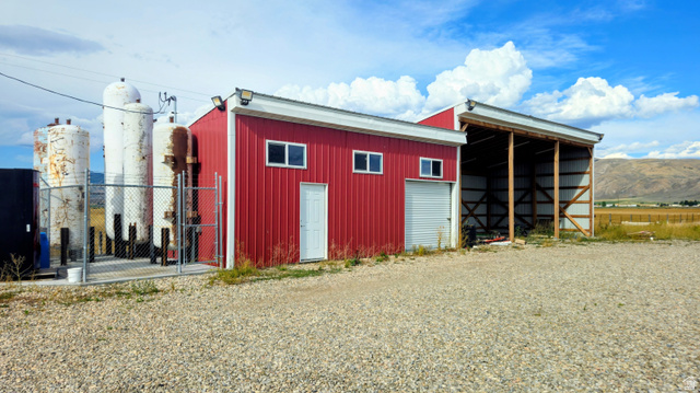 Red metal-sided building with white trim, featuring multiple windows and a garage door