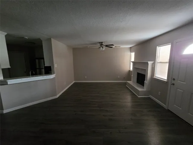 an empty room with wooden floor fireplace and windows