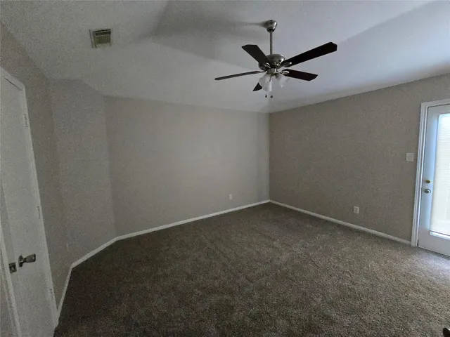 an empty room with a ceiling fan and window