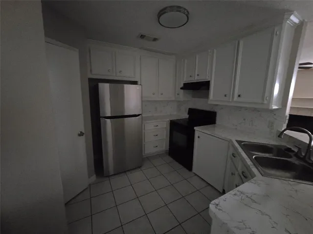 a kitchen with a refrigerator sink and cabinets