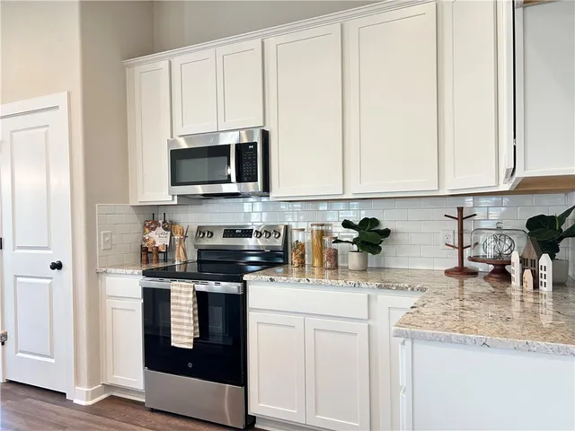 a kitchen with stainless steel appliances granite countertop a stove a sink and a microwave
