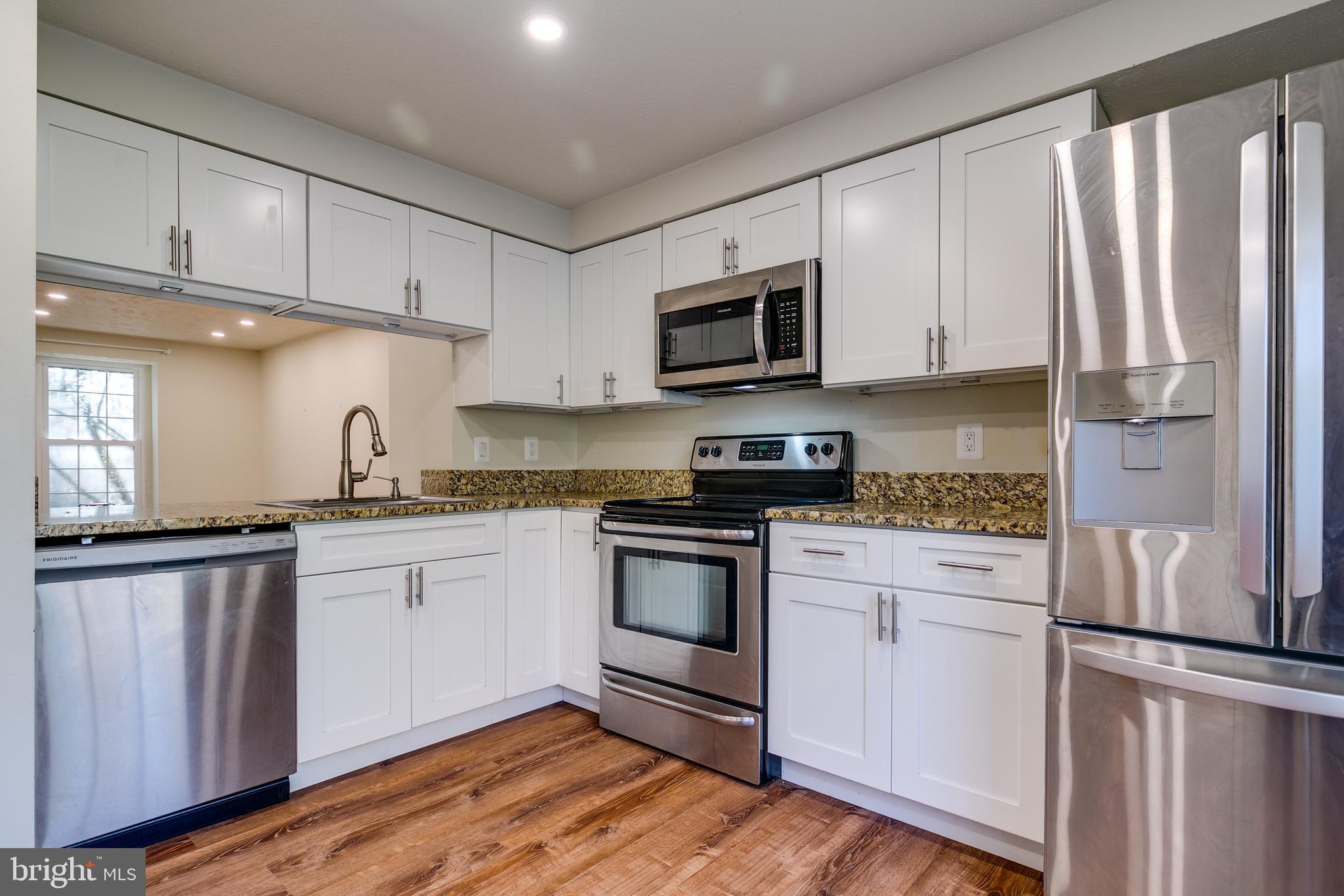 1589 Woodcrest Drive Reston, VA 20194 - Photo 13 of 29 a kitchen with granite countertop white cabinets and white appliances