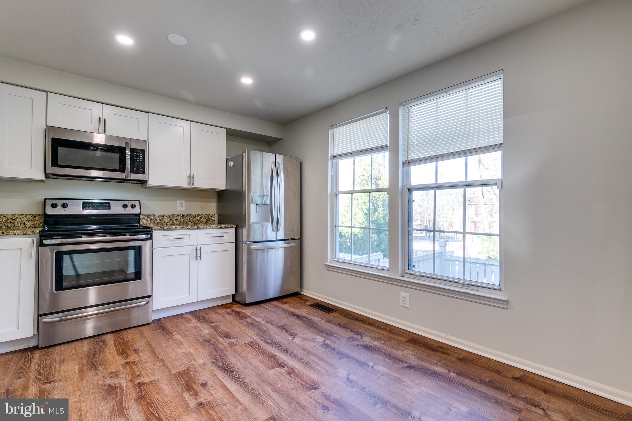 1589 Woodcrest Drive Reston, VA 20194 - Photo 10 of 29 a kitchen with stainless steel appliances a stove a microwave and white cabinets