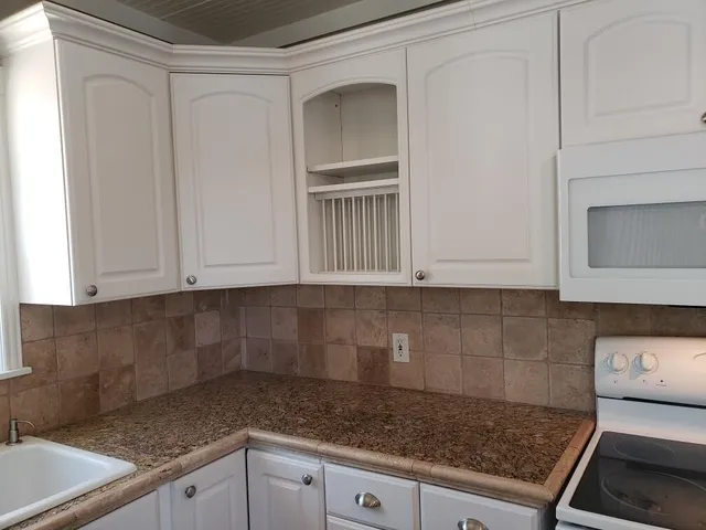 a kitchen with granite countertop white cabinets and a stove