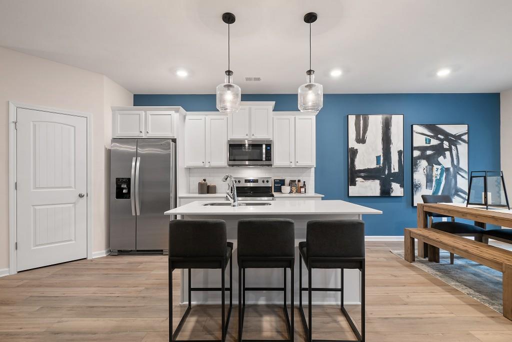 57 Scout Way Newnan, GA 30263 - Photo 7 of 37 a kitchen with stainless steel appliances granite countertop a stove a refrigerator a kitchen island a dining table and chairs with wooden floor