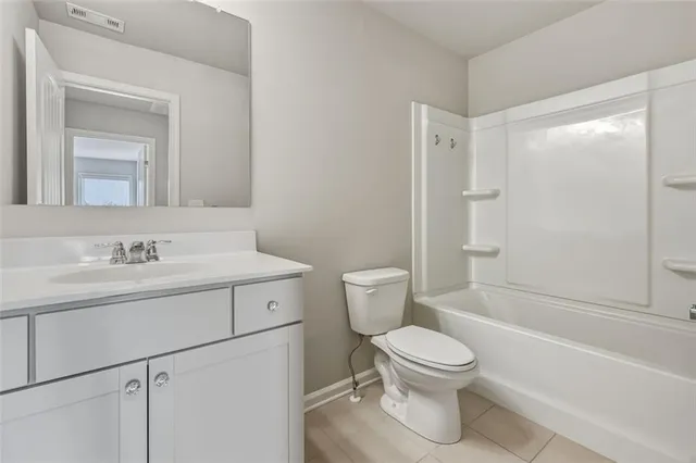 a bathroom with a toilet sink vanity granite and shower