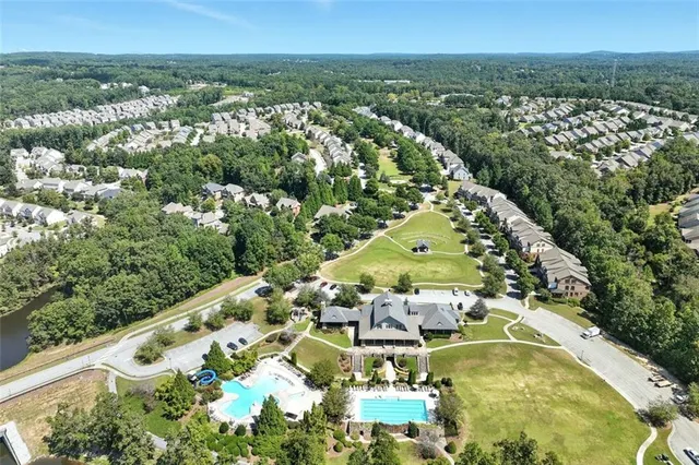 an aerial view of a residential houses with outdoor space and trees all around