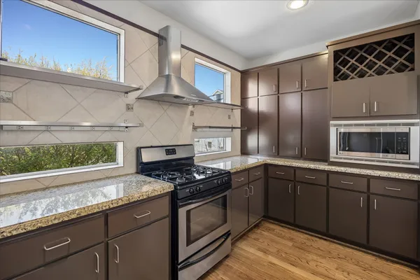 a kitchen with stainless steel appliances granite countertop a stove a sink and a microwave