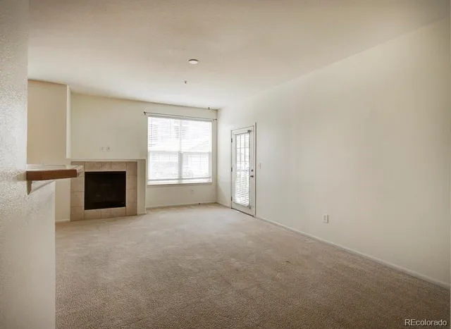 an empty room with windows and fireplace
