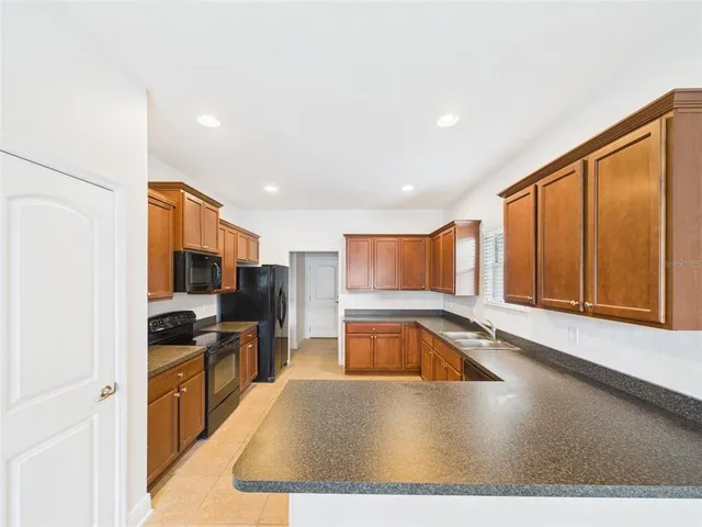 a kitchen with stainless steel appliances granite countertop a sink and a stove top oven with wooden floor
