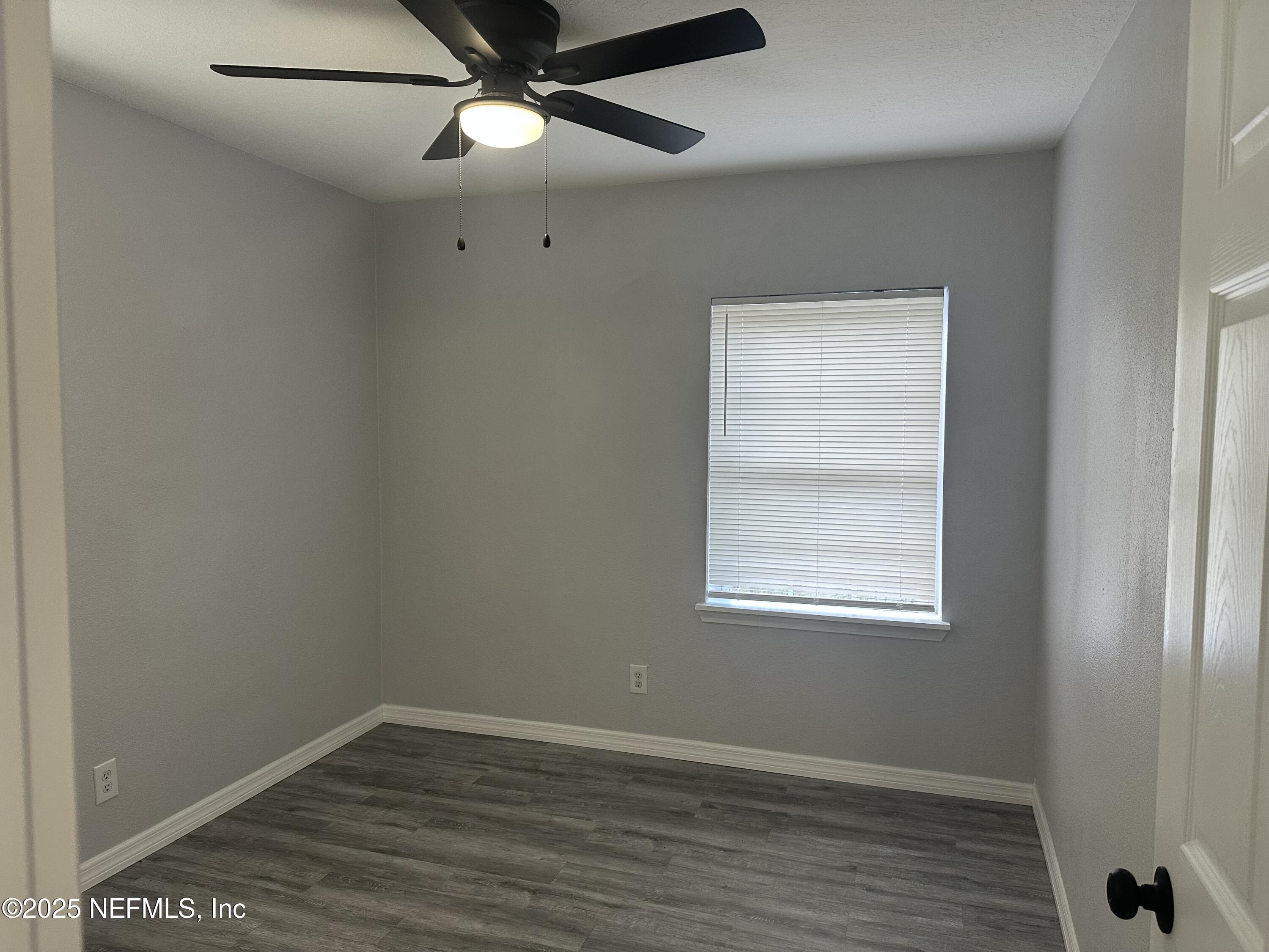 8049 Ramsgate Road Jacksonville, FL 32208 - Photo 12 of 14 an empty room with wooden floor fan and windows