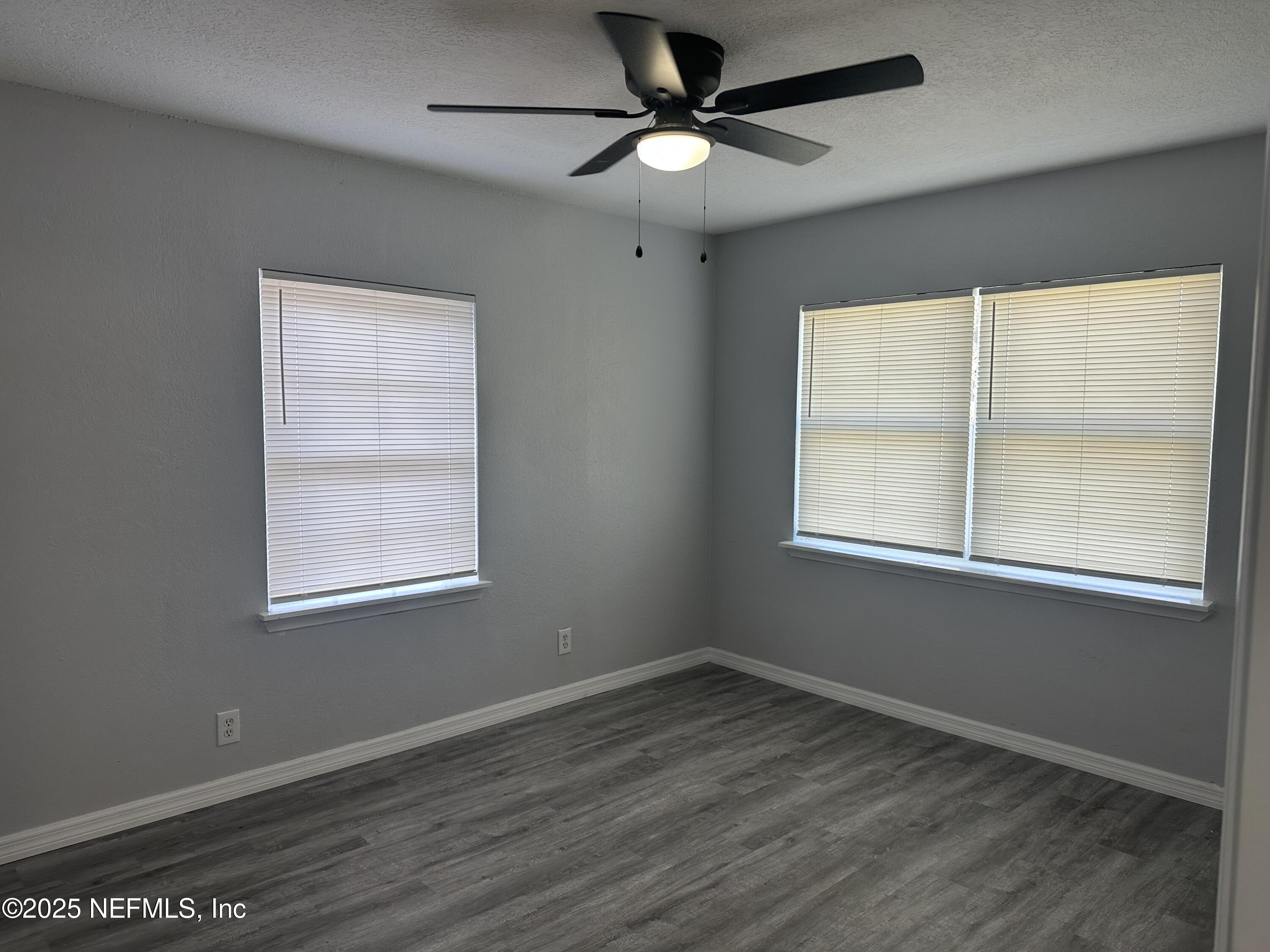 8049 Ramsgate Road Jacksonville, FL 32208 - Photo 13 of 14 an empty room with wooden floor ceiling fan and windows