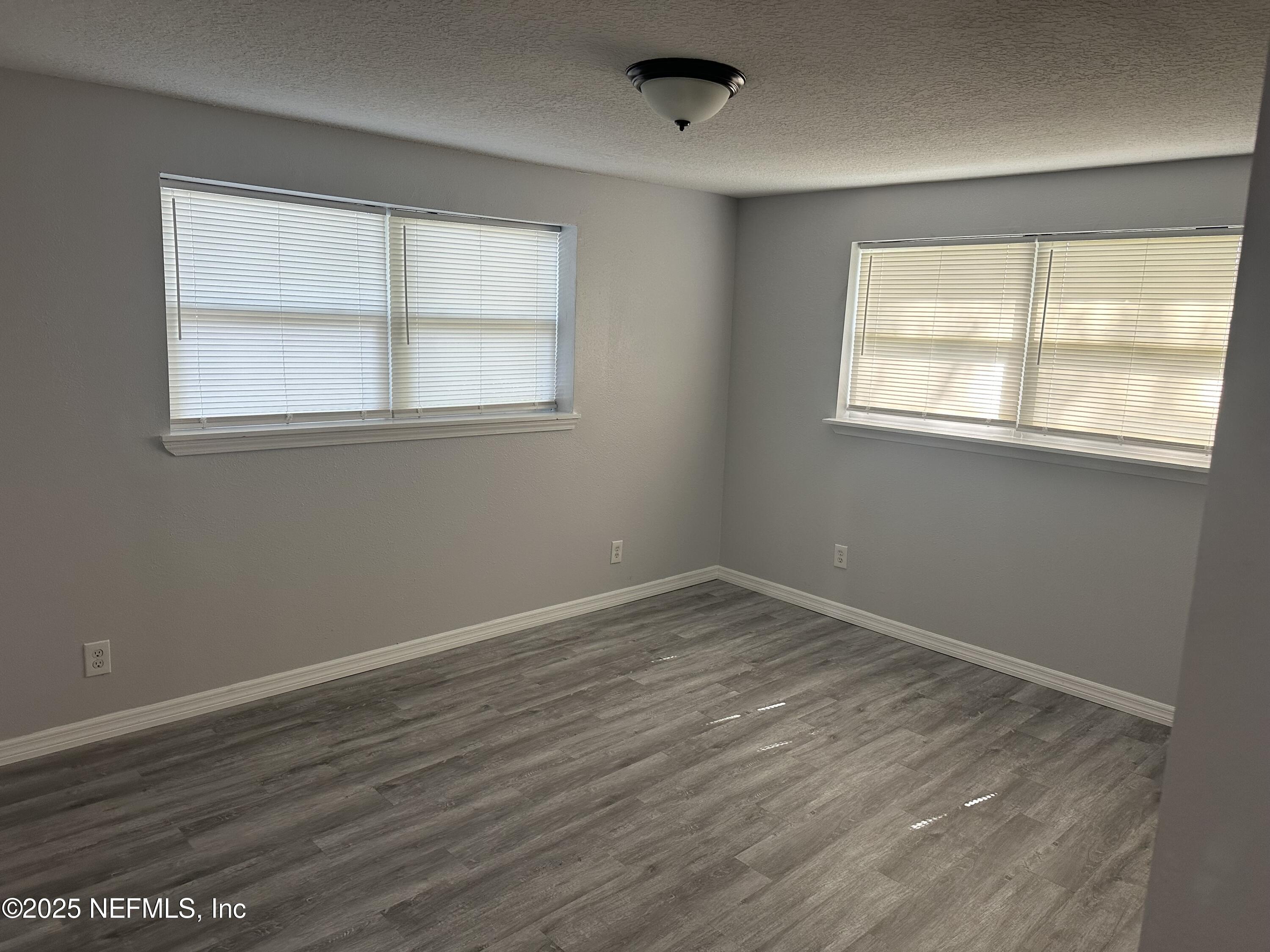 8049 Ramsgate Road Jacksonville, FL 32208 - Photo 7 of 14 a view of an empty room with wooden floor and a window