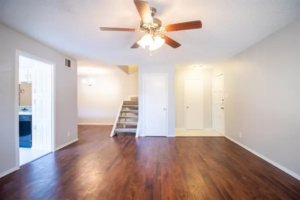 an empty room with wooden floor fireplace and windows