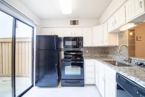 a kitchen with granite countertop a sink stainless steel appliances and cabinets