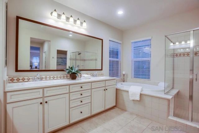 a bathroom with double vanity sink a two mirror a window a bathtub and a toilet