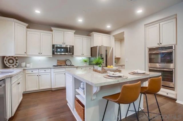 a kitchen with stainless steel appliances granite countertop a stove a sink a microwave a refrigerator and white cabinets