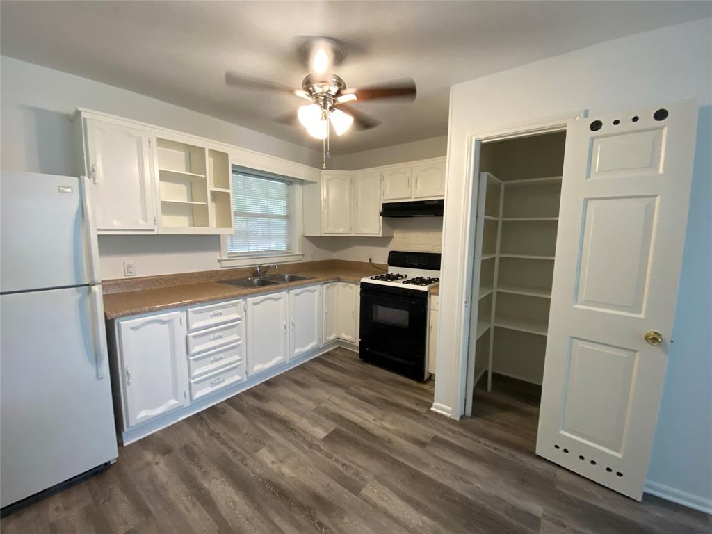 425 Wanda Way Hurst, TX 76053 - Photo 2 of 10 Kitchen featuring wood-finish flooring, white cabinetry, a double basin sink, and a built-in pantry with shelving