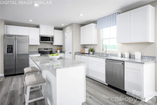 a kitchen with kitchen island granite countertop a sink cabinets and stainless steel appliances