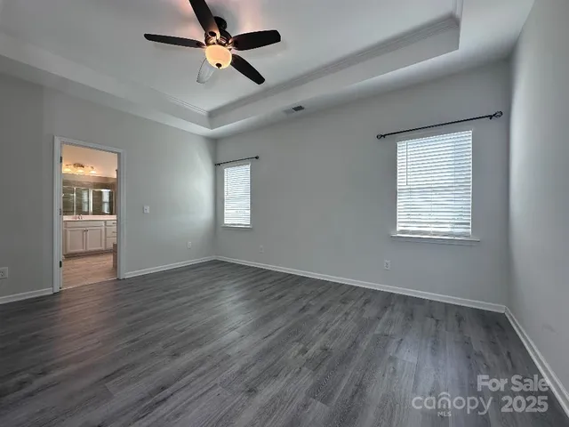 an empty room with wooden floor ceiling fan and windows