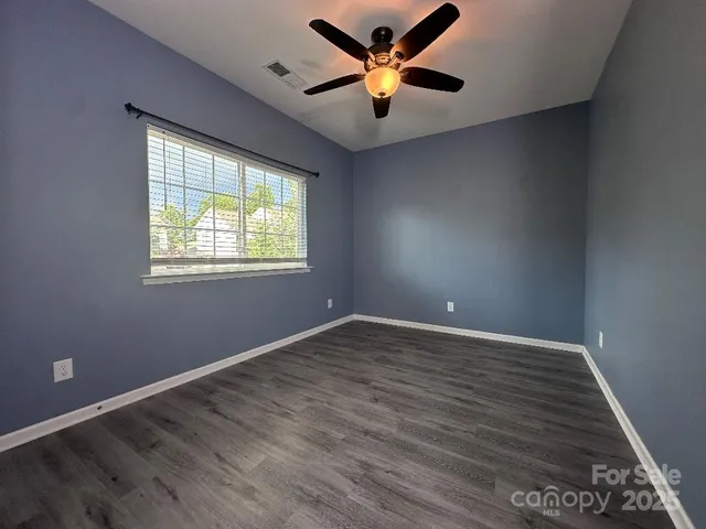 a view of an empty room with window and wooden floor