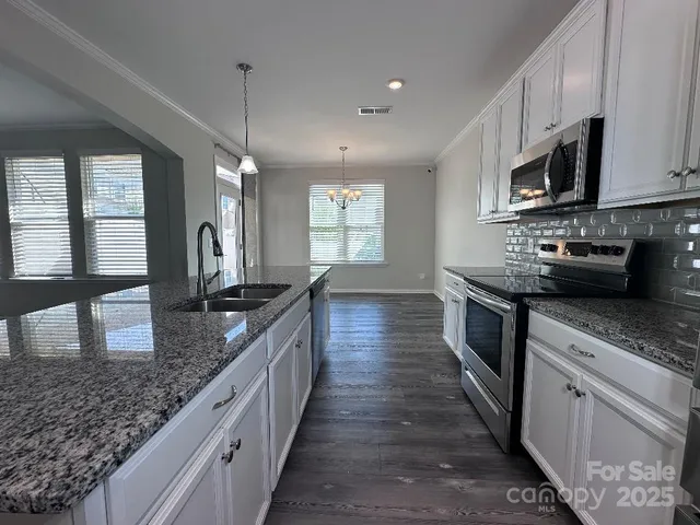 a large kitchen with stainless steel appliances granite countertop a lot of counter space