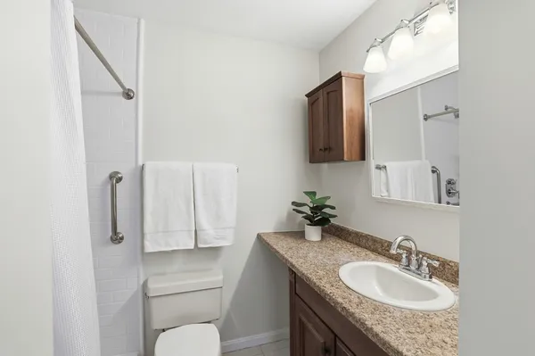 a bathroom with a granite countertop sink toilet and mirror