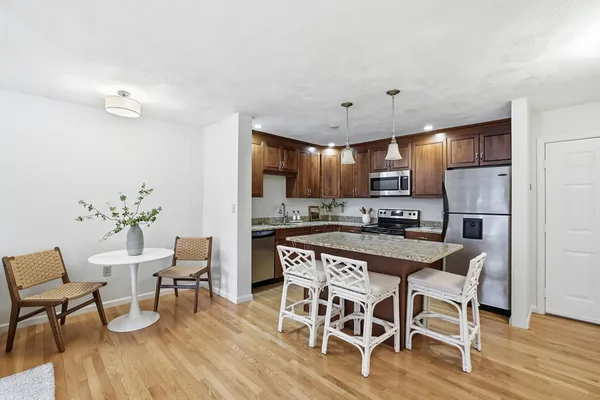 a kitchen with stainless steel appliances a dining table chairs and wooden floor