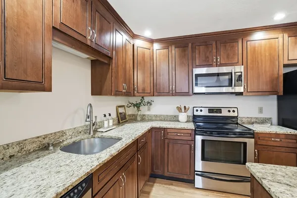 a kitchen with granite countertop a stove sink and microwave