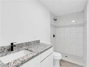 a bathroom with a granite countertop sink a toilet and shower