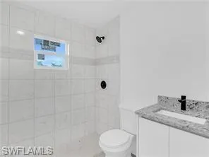 a bathroom with a granite countertop sink a toilet and shower